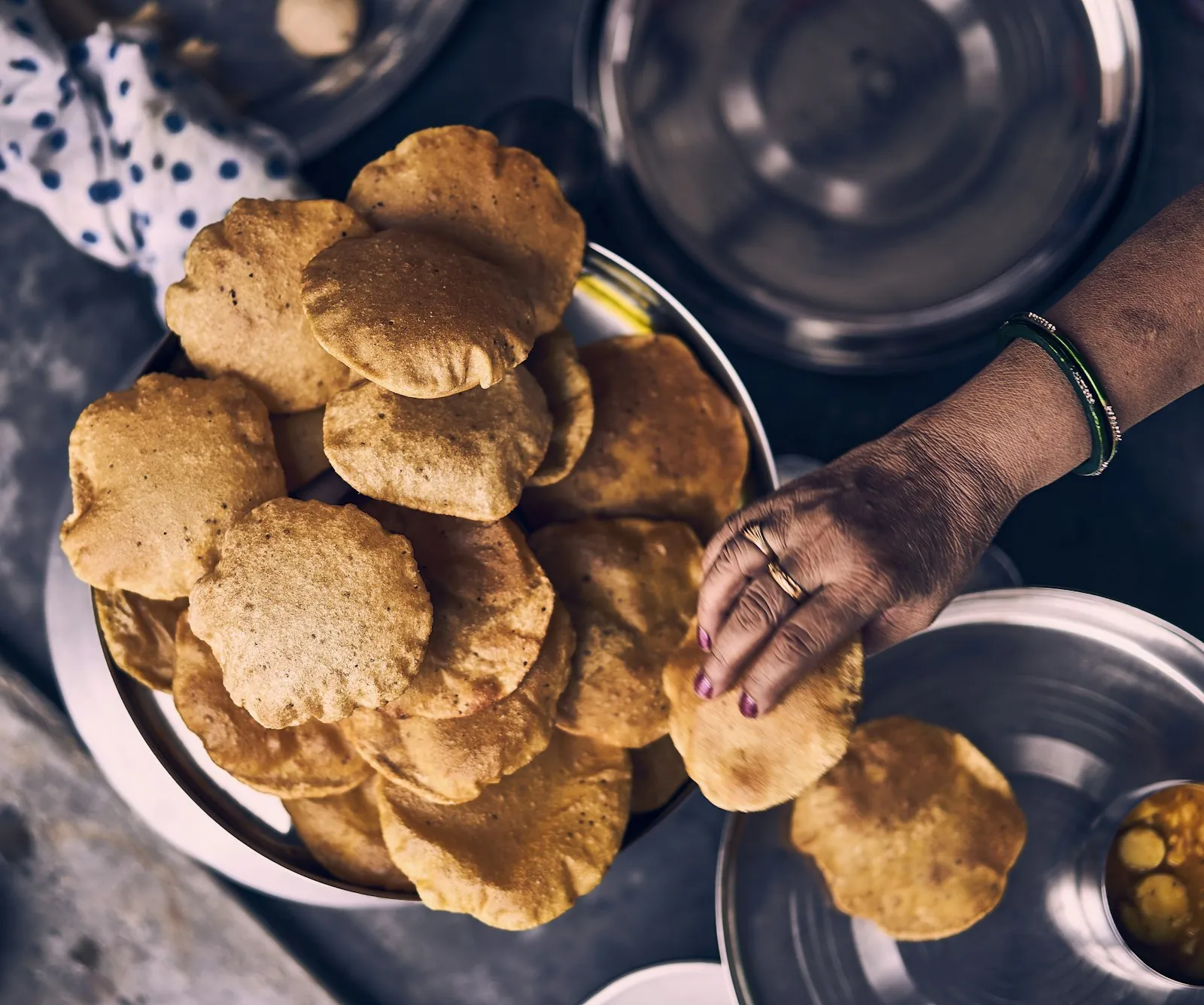 Hands lifting freshly made bread from a steel plate on a work surface