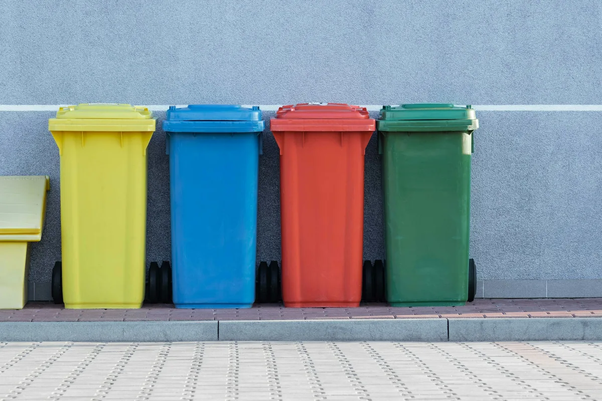 Segregated waste bins lined up against a wall