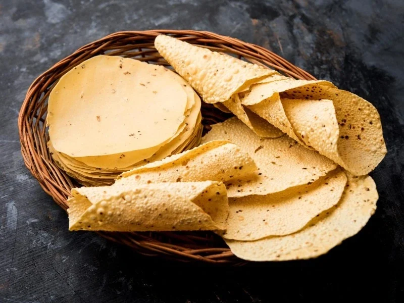 Thick Punjabi style papad, rolled and stacked in a cane basket